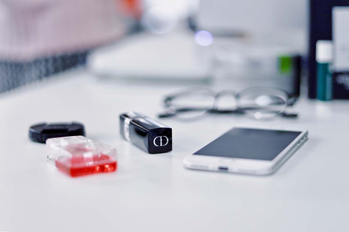 mobile phone white smartphone and black framed eyeglasses behind phone